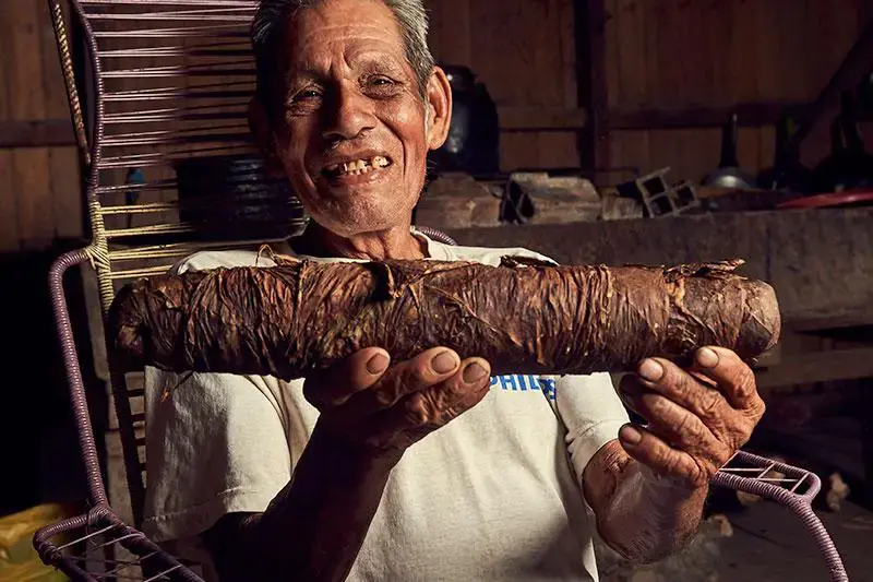 Elder holding a mapacho log