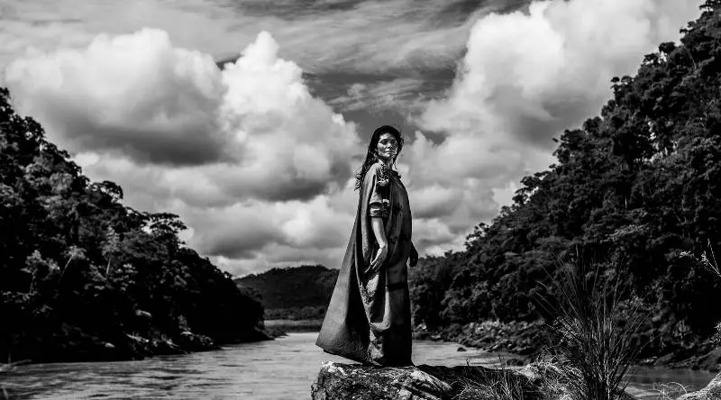 Woman in a ceremonial cloak by an Amazon river